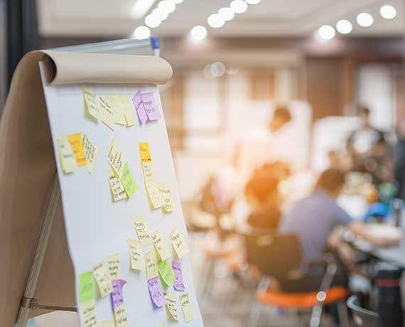 Large notepad with sticky notes in the foreground with a workshop in the background