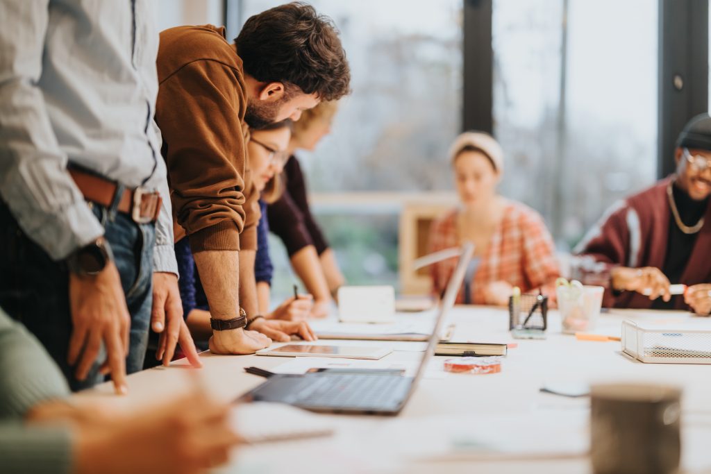 A group of diverse colleagues collaborating during a business meeting in a bright, contemporary office space, reflecting teamwork and strategy.